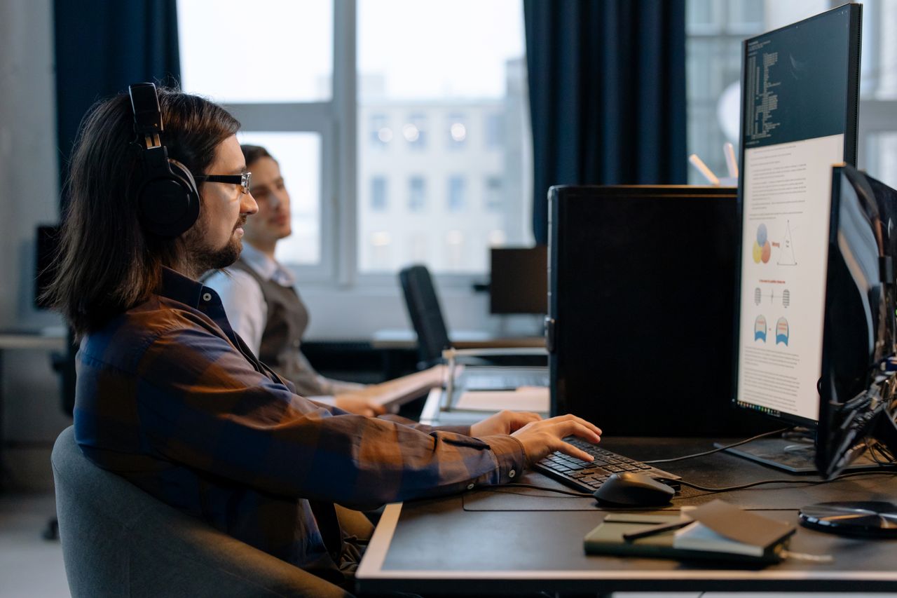 Home Two programmers working together with focus on coding in a modern, tech-savvy office environment.